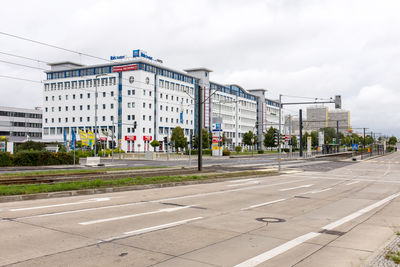 Road by buildings against sky in city