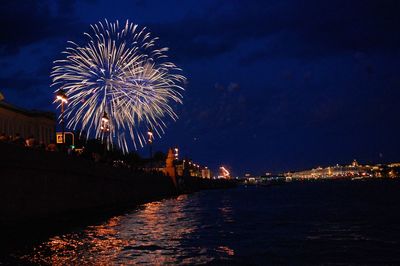 Firework display over river against sky at night