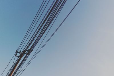 Low angle view of electricity pylon against clear blue sky