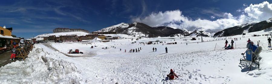 Panoramic view of people on snowcapped mountains against sky