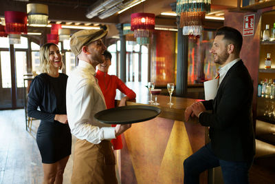 Smiling friends talking with bartender