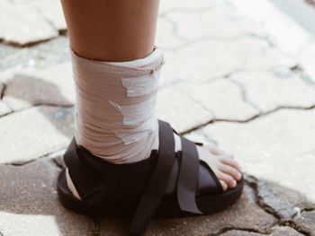 Low section of woman with elastic bandage standing on footpath