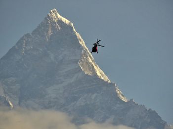 Low angle view of helicopter on snowcapped mountain against sky