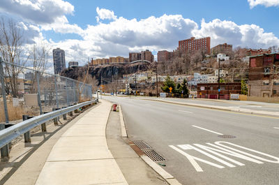 Road amidst buildings in city against sky