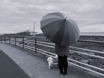 Black and white monochrome woman standing under an umbrella at the beach