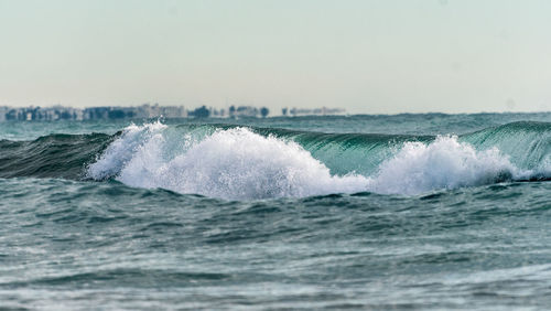 Waves splashing in sea against clear sky