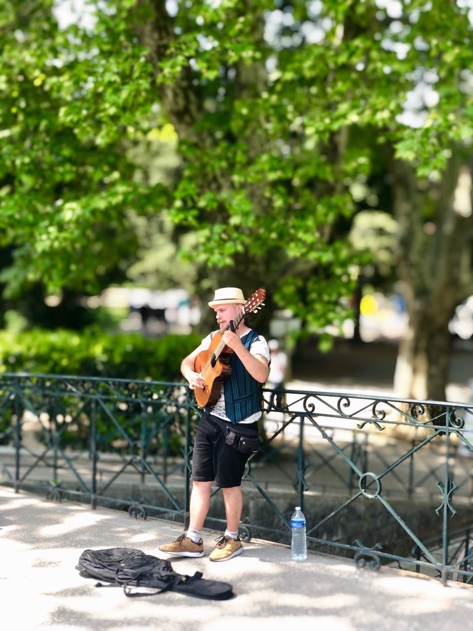 MAN PHOTOGRAPHING WITH MOBILE PHONE WHILE STANDING BY TREES