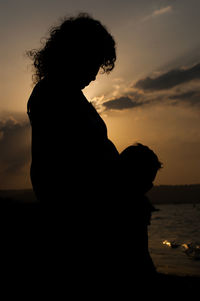 Silhouette mother and son standing on beach