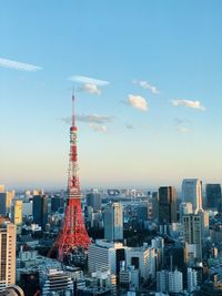 Communications tower in city against sky