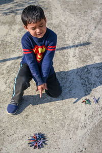 High angle view of boy pointing while playing with clothespin on land