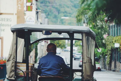 Rear view of man sitting in vehicle