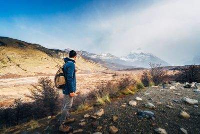 Rear view of man walking on mountain against sky