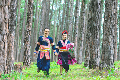 Full length portrait of a smiling young woman in forest