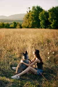 Side view of woman sitting on grassy field