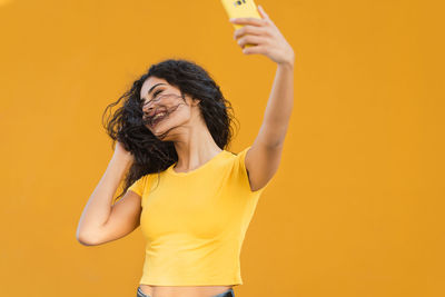 Full length of a smiling young woman against yellow background