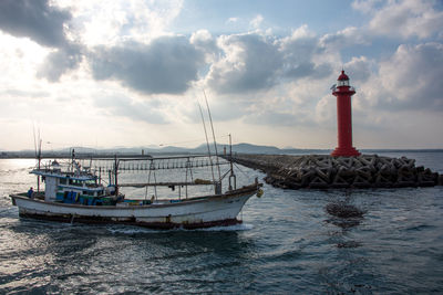 Lighthouse by sea against sky