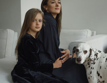 Portrait of woman with daughter and dog sitting at home