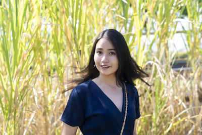 Portrait of smiling woman standing by plants