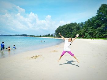 Boy playing on beach against sky