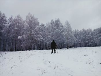 Person standing on snow covered landscape against trees