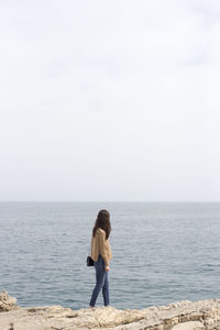 Side view of woman at beach against sky