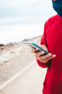 Midsection of man using mobile phone against sea