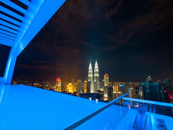 Illuminated cityscape against blue sky at night