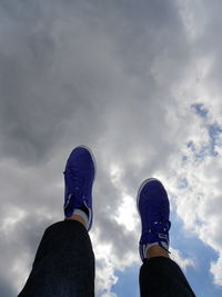 Low angle view of person against cloudy sky