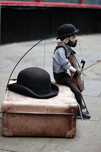 Close-up of figurine with hat and suitcase on road