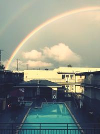 Rainbow over buildings in city against sky during sunset