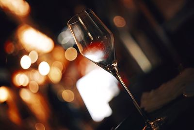 Close-up of empty wineglass on table against illuminated lights