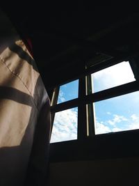 Low angle view of silhouette man against sky seen through window
