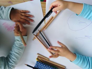 Cropped hands of children drawing on cardboard