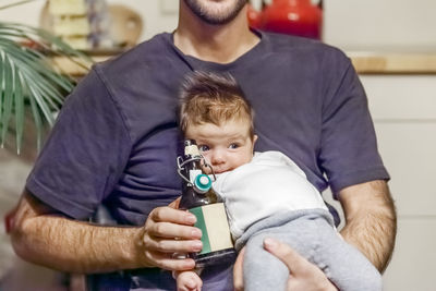 Midsection of father with beet bottle carrying cute daughter while sitting at home