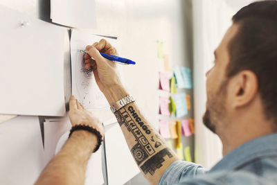 Mid adult businessman writing on paper in office