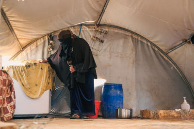 A refugee woman works inside her tent. syrian refugees.