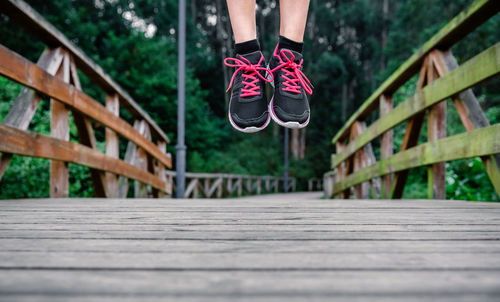 Low section of woman jumping on footbridge