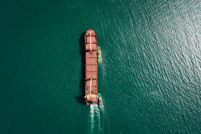 Aerial top view tugboat pulling red oil ship to shipyard dry dock repairing and maintenance in sea