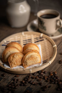 Fried curry puffs on a rattan plate with a cup of coffee. malaysian snacks. malaysian breakfast. 