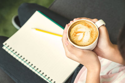 Midsection of person holding cappuccino