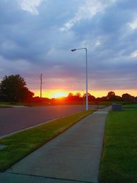 Road by landscape against sky during sunset