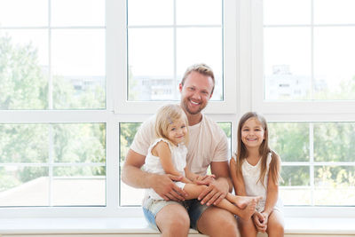 Father sitting with daughters against window