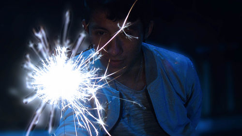 Close-up of man holding illuminated sparkler