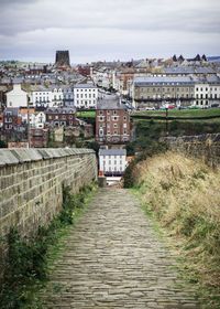 Footpath amidst buildings in town against sky