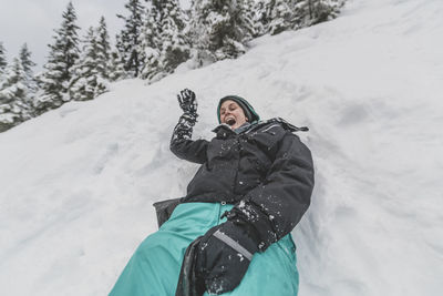 Young woman with hat sliding fast in the snow downhill funny face