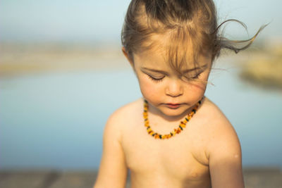 Portrait of shirtless boy at beach against sky