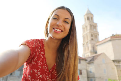 Portrait of smiling woman standing against buildings in town