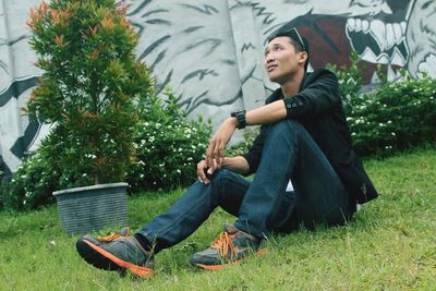 Side view of young man sitting on grass