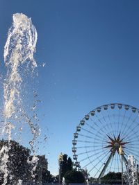 Low angle view of ferris wheel against blue sky