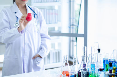 Midsection of female doctor standing by table in laboratory